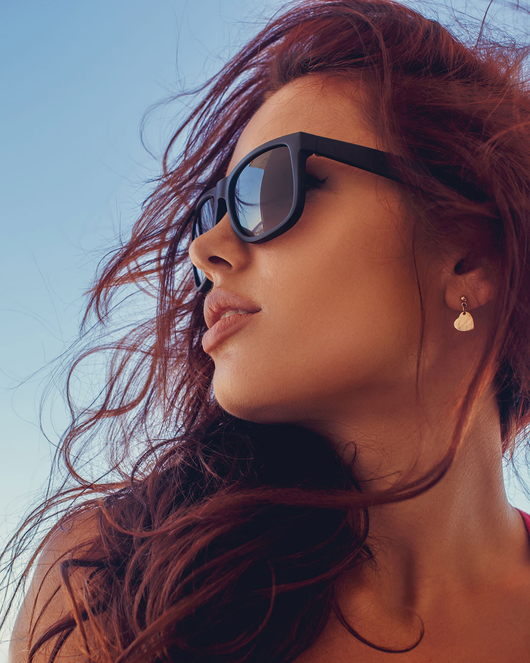 Frau mit Sonnenbrille genießt selbstbewusst den Sommertag – neues Lebensgefühl nach der Nasenkorrektur